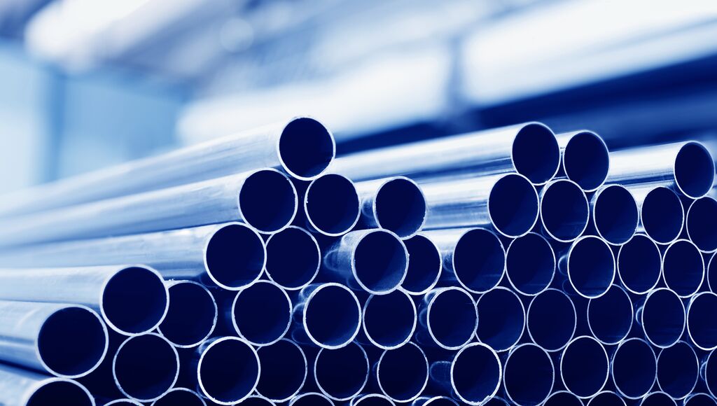 Steel tubes against industrial blurred background.