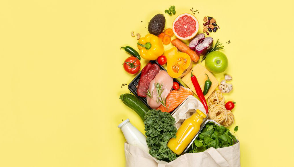 A bag filled with an assortment of fresh produce, including fruit, vegetables, meat, eggs, arranged in a spill-out layout.